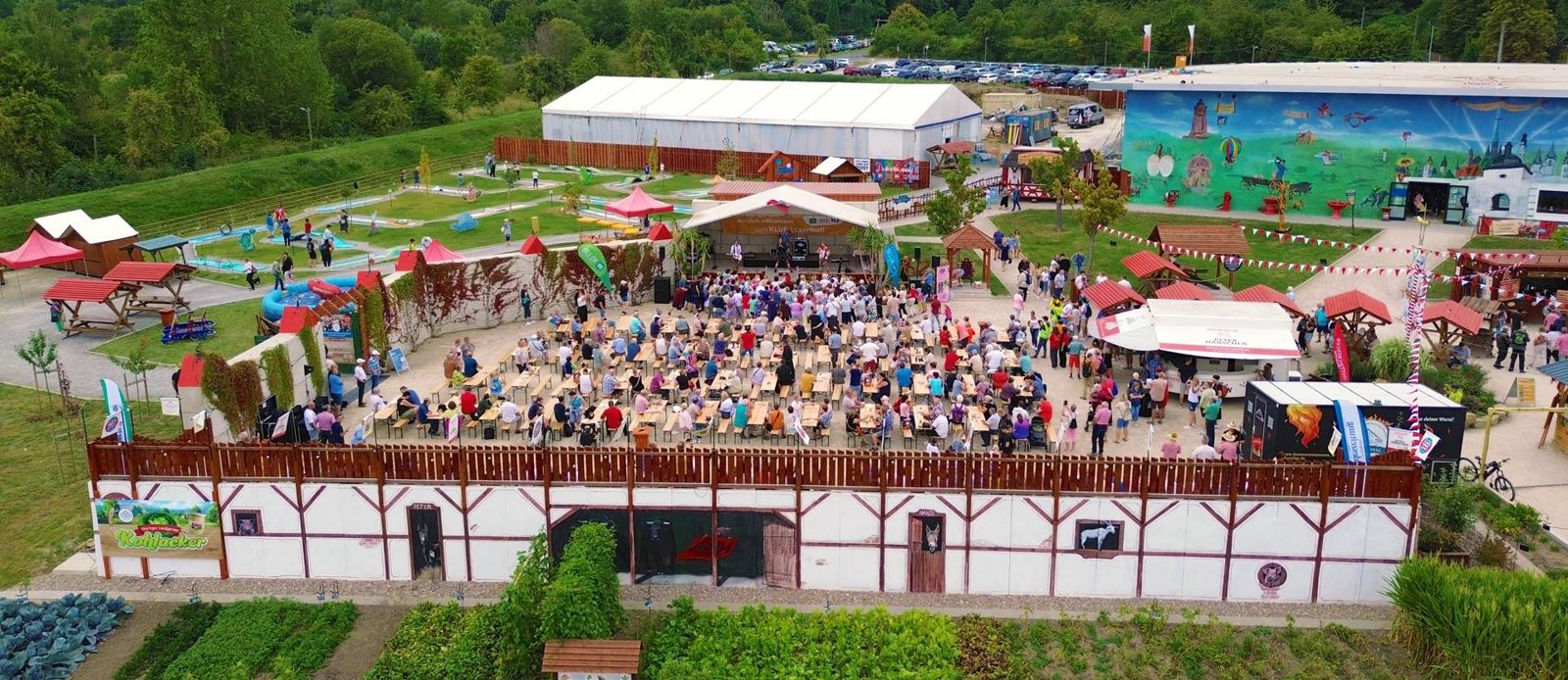 Luftaufnahme des Freigeländes vom 1. Deutschen Bratwurstmuseum in Mühlhausen mit Festplatz, Minigolf und bemalter Museumsfassade